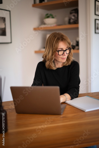 Mature adult woman remote working on laptop at home