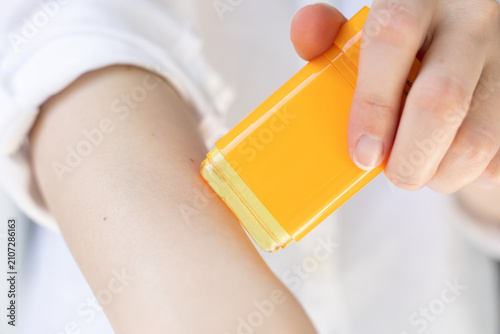 Closeup of a woman applying stick sunscreen.