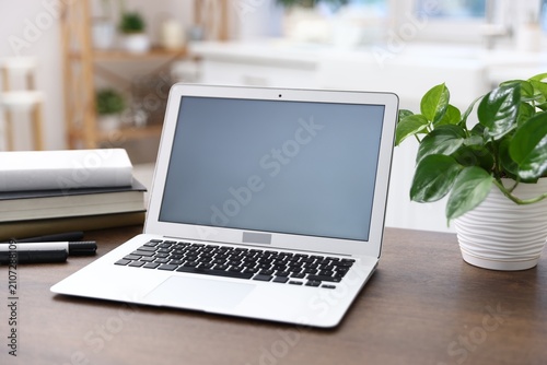 Comfortable workplace with laptop on wooden table indoors