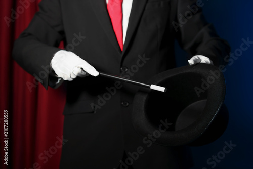 Photos Magician showing trick with wand and top hat on stage, closeup