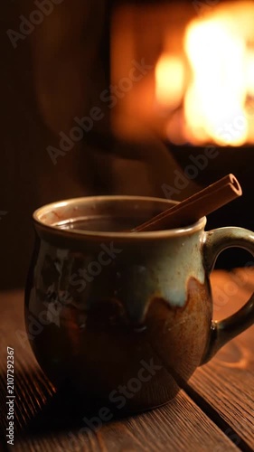 Hot steaming drink in a ceramic mug resting by a cozy fireplace at home