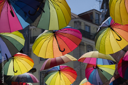 Colorful rainbow umbrellas suspended above Pink Street in Lisbon Portugal creating a vibrant urban canopy