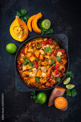 Slow cooked casserole dish  healthy yummy spicy Italian one-pan role stew vegetable pumpkin, sweet potato, chicken and rice served as top view in a design casserole