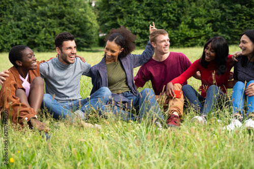 Multiracial Friends Sitting in Grass Field Laughing Together