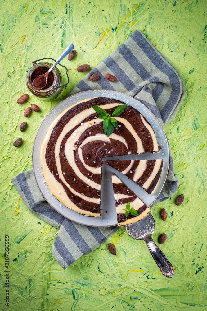 Naklejka premium Artisan homemade baked zebra black-white cheesecake pie with dark chocolate served as top view on a design plate