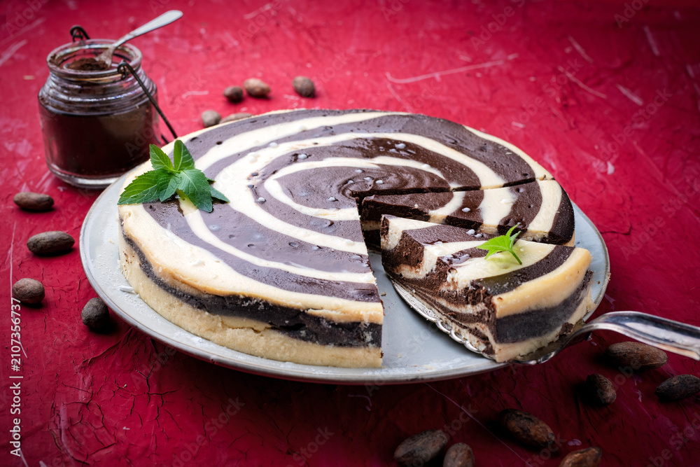 Fototapeta premium Artisan homemade baked zebra black-white cheesecake pie with dark chocolate served as close-up on a design plate
