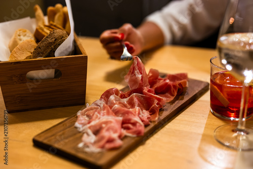Italian aperitivo with charcuterie board prosciutto salami and red Negroni cocktail at bar