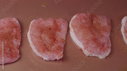 Seasoned pork chops cooking on a flat top griddle