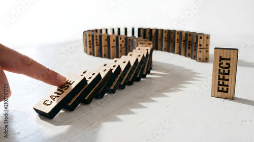 Wooden dominoes labelled cause and effect showing chain reaction concepts.