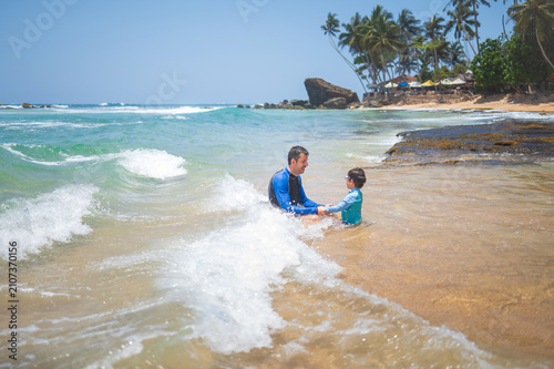 Caucasian father and son playing in shallow tropical waters on Sri Lankan beach