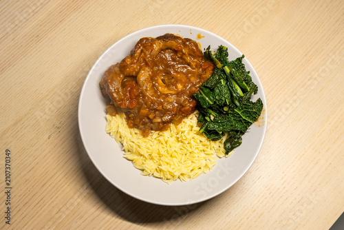 Foto A plate of osso buco with kale and orzo.