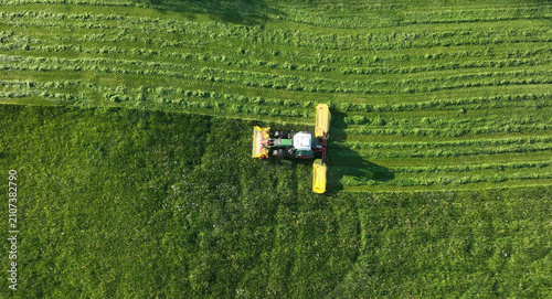 Drohnenaufnahme von einem Traktor der im Sommer ein Feld mäht