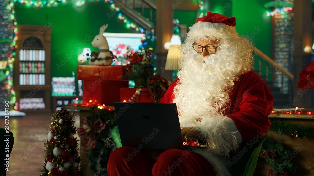 Fototapeta premium Smiling Santa Claus posts online to spread positivity and holiday joy while helping children feel a sense of wonder during Christmas.
