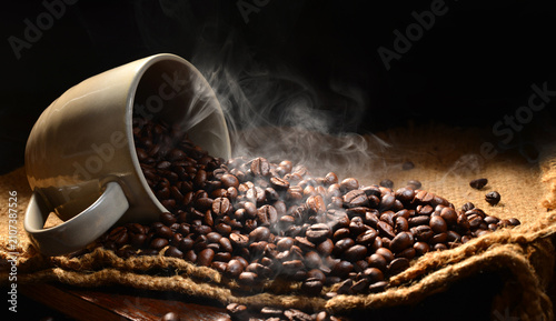 Bild auf Leinwand Steaming roasted coffee beans spilling from a ceramic cup onto rustic burlap, hi