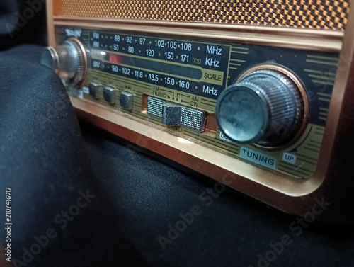 Obraz na płótnie A vintage portable analog radio with a classic wooden cabinet, woven speaker grille, and silver tuning knobs