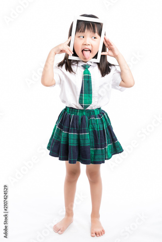 Playful Asian girl in school uniform looking through a white frame making a funny face.