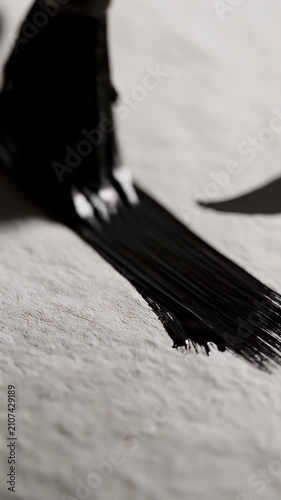 Calligraphy brush with black ink on textured paper.