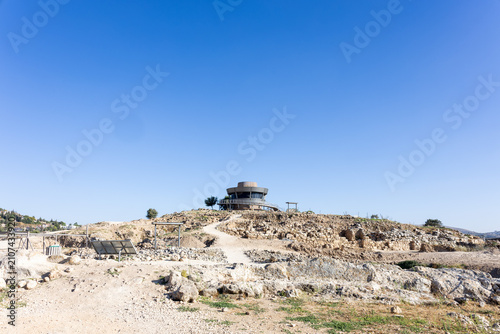 Фотография Modern circular observation structure sitting atop a rocky hill at an archaeological excavation site under a vast blue sky