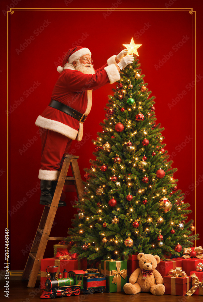 Fototapeta premium Santa Claus Decorating Christmas Tree with Glowing Star Topper.