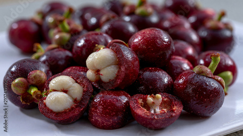 Heap of fresh purple mangosteen fruits on a white plate with mangosteen tropical nutrition