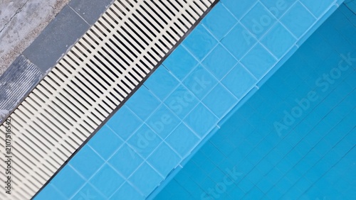 Blue swimming pool tiles with drainage grating background pattern
