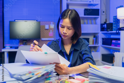 Young Asian businesswoman reviewing documents while working in office, business administration and paperwork concept.