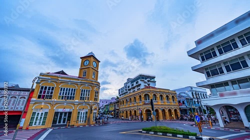 Time lapse Blue hour view of the historic clock tower in Phuket Old Town, Thailand, featuring beautifully preserved Sino-Portuguese architecture, dramatic clouds, and motion-blurred city traffic.