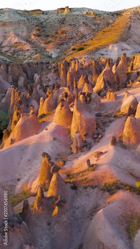 Vertical video. Goreme, Nevsehir, Turkey. Devrent Valley fairy chimneys and hoodoo rock formations, aerial panoramic view at golden hour over the eroded volcanic landscape. Aerial View. Rich colors