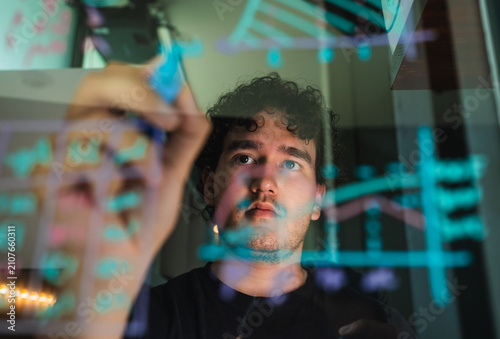 Принти на полотні Man analyzing data and visualizing graphs on transparent screen