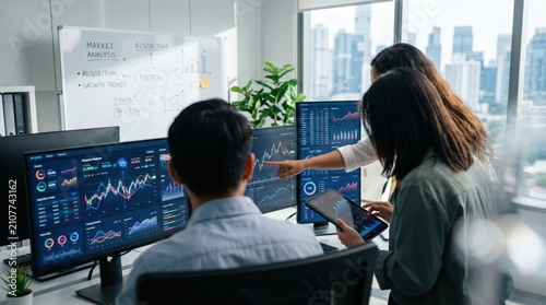 Business team analyzing financial market trends on multiple computer screens, pointing at stock graphs, fintech algorithm discussion in modern office with city view, professiona...