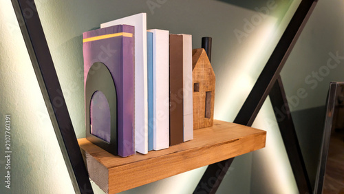 Принти на полотні Modern Wooden Floating Shelf with Colorful Books, Metal Bookend, and Cozy Ambien