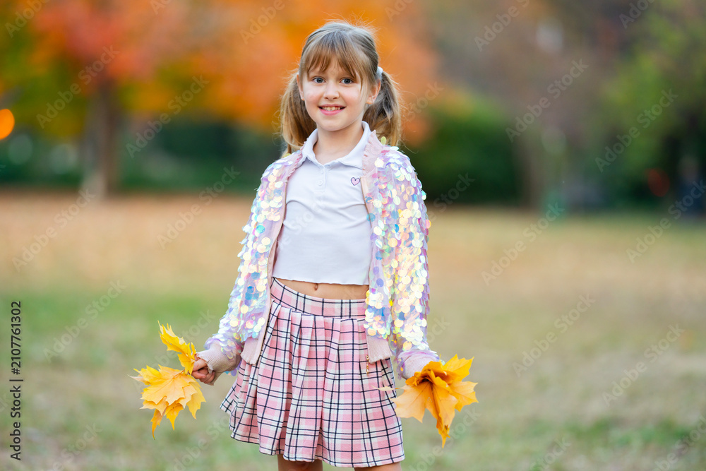 Obraz premium Autumn girl holds foliage. Autumn kid smiles. Colorful autumn portrait. Cute autumn daylight.
