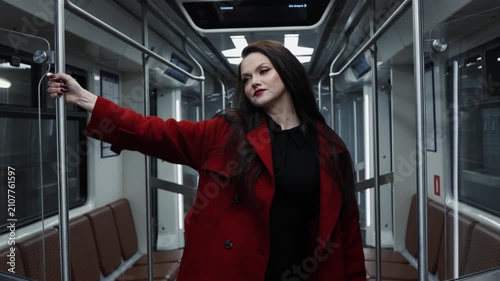 An elegant brunette in a crimson coat riding the metro, city life and street fashion
