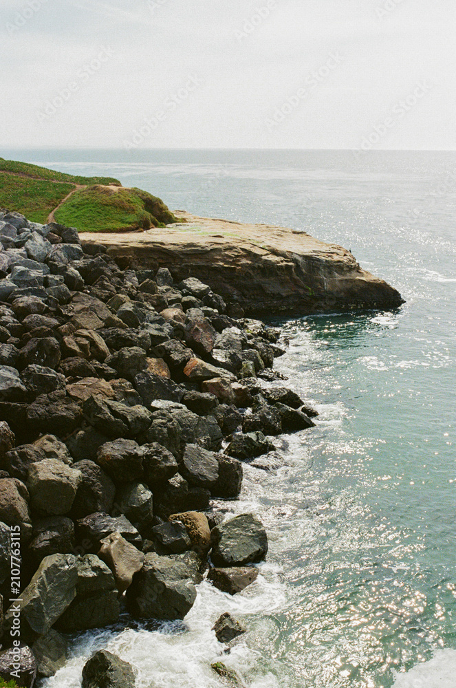 Fototapeta premium Sunlit rocky shore with sparkling ocean water