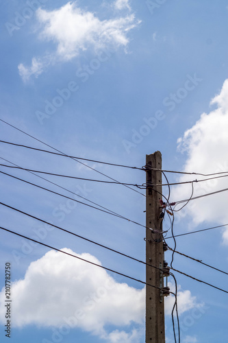 An upward view of a towering concrete utility pole with electric wires slicing through a vivid blue sky an intense perspective showcasing structure, tension, and power