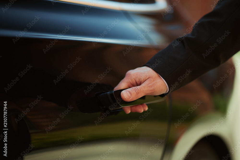 Obraz premium Close up of middle aged businessman opening car door, showing executive mobility, transport access, commuting concept. Useful for corporate travel, automotive service, insurance ads