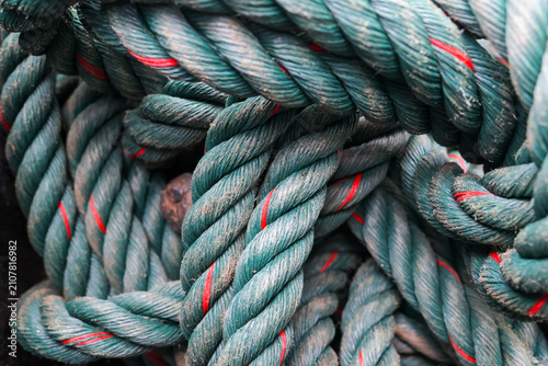 Fotografie Thick teal rope coil with red tracer and weathered texture, closeup showing brai