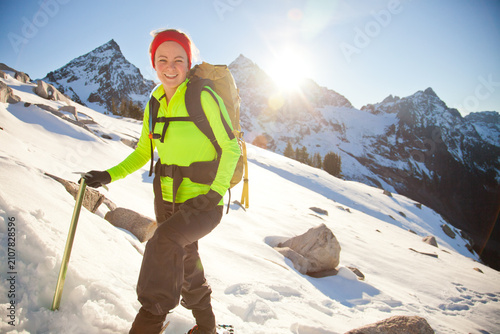Smiling woman hiking up a snowy mountain