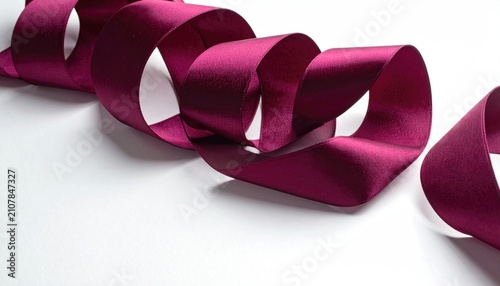 A rich, crimson satin ribbon elegantly curls across a bright white background