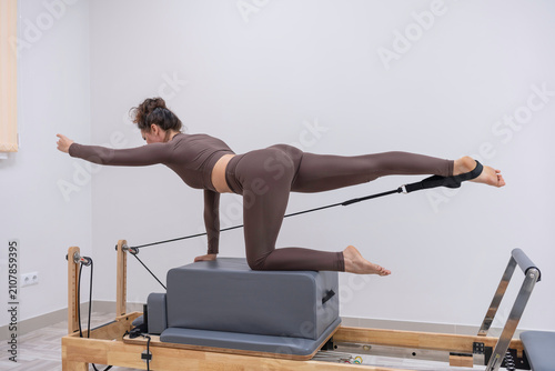 Fotografía Core strengthening bird dog pose performed by focused woman on pilates reformer
