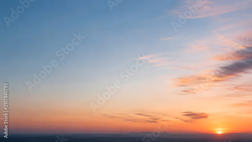 地平線に沈む夕日とオレンジから青へのグラデーションの空