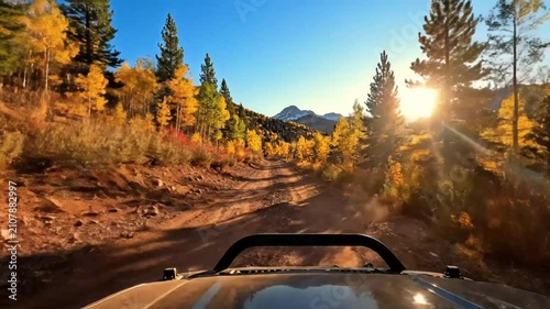 Scenic off-road adventure through autumn forest with colorful trees and mountain views on a sunny day