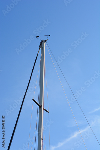 Fotografie A vertical low angle shot of a sailboat aluminum mast with rigging wires and a w
