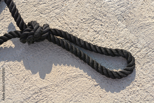Konstfotografi A close up shot of a thick black nylon marine mooring rope forming a loop with a