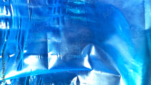 Closeup of a crumpled blue plastic sheet with light reflections and shadows