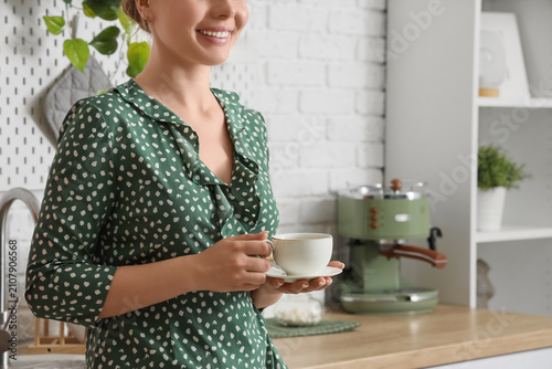 Young woman with cup of espresso near modern coffee machine in kitchen