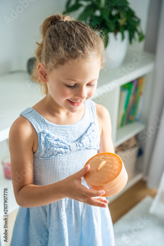 Child prepares to open a surprise squishy toy container at home. Anticipation and curiosity drive the excitement of discovering a hidden collectible.