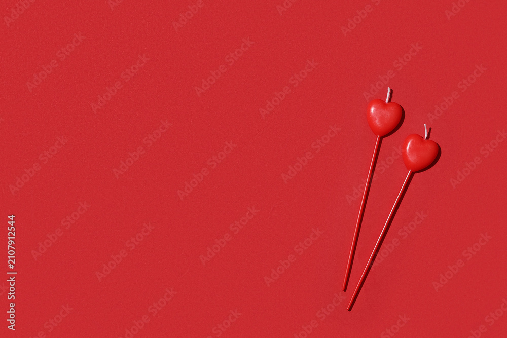 Fototapeta premium Candles in shape of heart on red background. Valentines Day celebration
