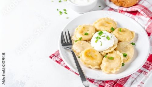 Polish pierogi dumplings served with sour cream on a bright white copy space background, authentic homemade style
