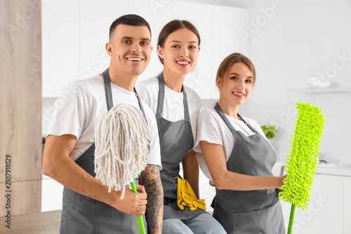 Team of young janitors with mops in kitchen